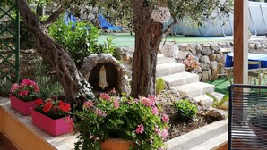 A covered outdoor area with a stone bench, a hanging bird feeder, and a small shrine.