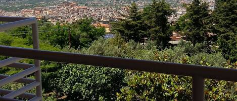 A balcony with a view of a coastal cityscape, including buildings and the sea.