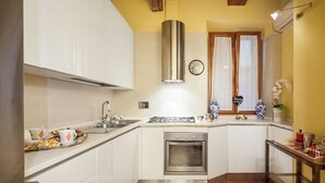 A kitchen with white cabinets, a stainless steel range hood, a built-in oven, and a window with curtains. - Navona Apartment (Piazza Navona San Pietro Castel Sant'Angelo Campo dè Fiori) (Roma)