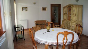 Ein Esszimmer mit einem runden Tisch, Stühlen, einem Schrank und einem Heizkörper.