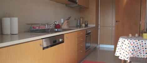 Une cuisine moderne avec des meubles en bois, un évier en acier inoxydable et un coin repas agrémenté d’une nappe à pois.
