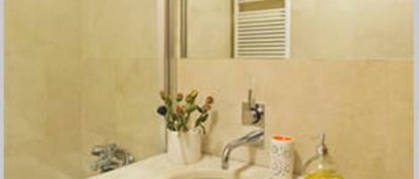 Baño con lavamanos, espejo y ducha.