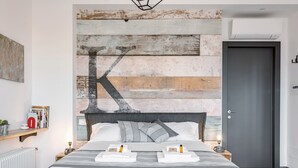 A modern bedroom with a large bed, a rustic wall design, and a door. - Studio Vaticano Int. 5B - Terrace with View on San Pietro (Roma)