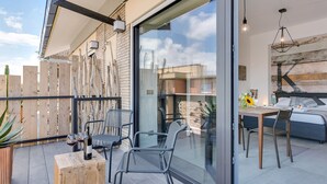 A modern outdoor patio with a dining area, a wooden table, and chairs. - Studio Vaticano Int. 5B - Terrace with View on San Pietro (Roma)