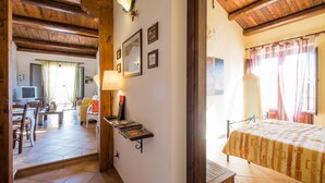 A hotel room with a bed, a desk, and a chair. There is a window with curtains and a lamp on the wall. - Bright Penthouse With Terrace On Via Maqueda, In The Heart Of The City (Palermo)