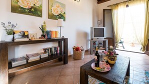 A living room with a television, bookshelves, a table with a bottle and glasses, and two paintings of roses. - Bright Penthouse With Terrace On Via Maqueda, In The Heart Of The City (Palermo)