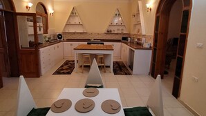 Une cuisine compacte avec des meubles blancs, un îlot central et un coin repas comprenant une table et des chaises.