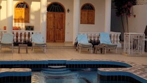 Un espace piscine avec des chaises longues et une porte en bois.
