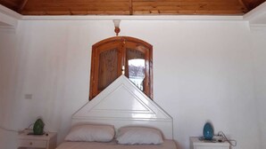 Une chambre à coucher avec un plafond en bois, un lit, une table de chevet et une commode.