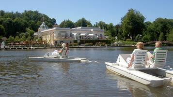 A boat with two people and a child on board, a casino building in the background, and a calm lake.