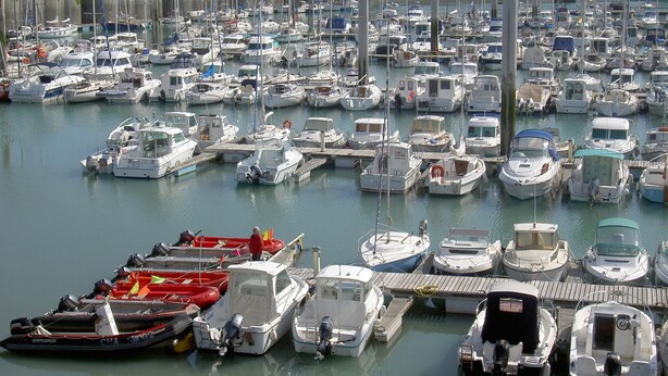Un port de plaisance où de nombreux bateaux de différentes sortes sont amarrés à des quais en bois.