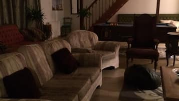 Een woonkamer met een bank, een houten stoel, een tafel en een trap.