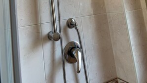 A shower with a handheld showerhead and a wall-mounted faucet.