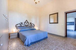 A bedroom with a bed, a nightstand, a mirror, and a door leading to a bathroom. - "TERRACE BELL" (PANZANO IN CHIANTI)