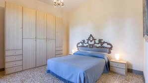 A bedroom with a large wardrobe, a bed with a decorative headboard, and a chandelier. - "TERRACE BELL" (PANZANO IN CHIANTI)