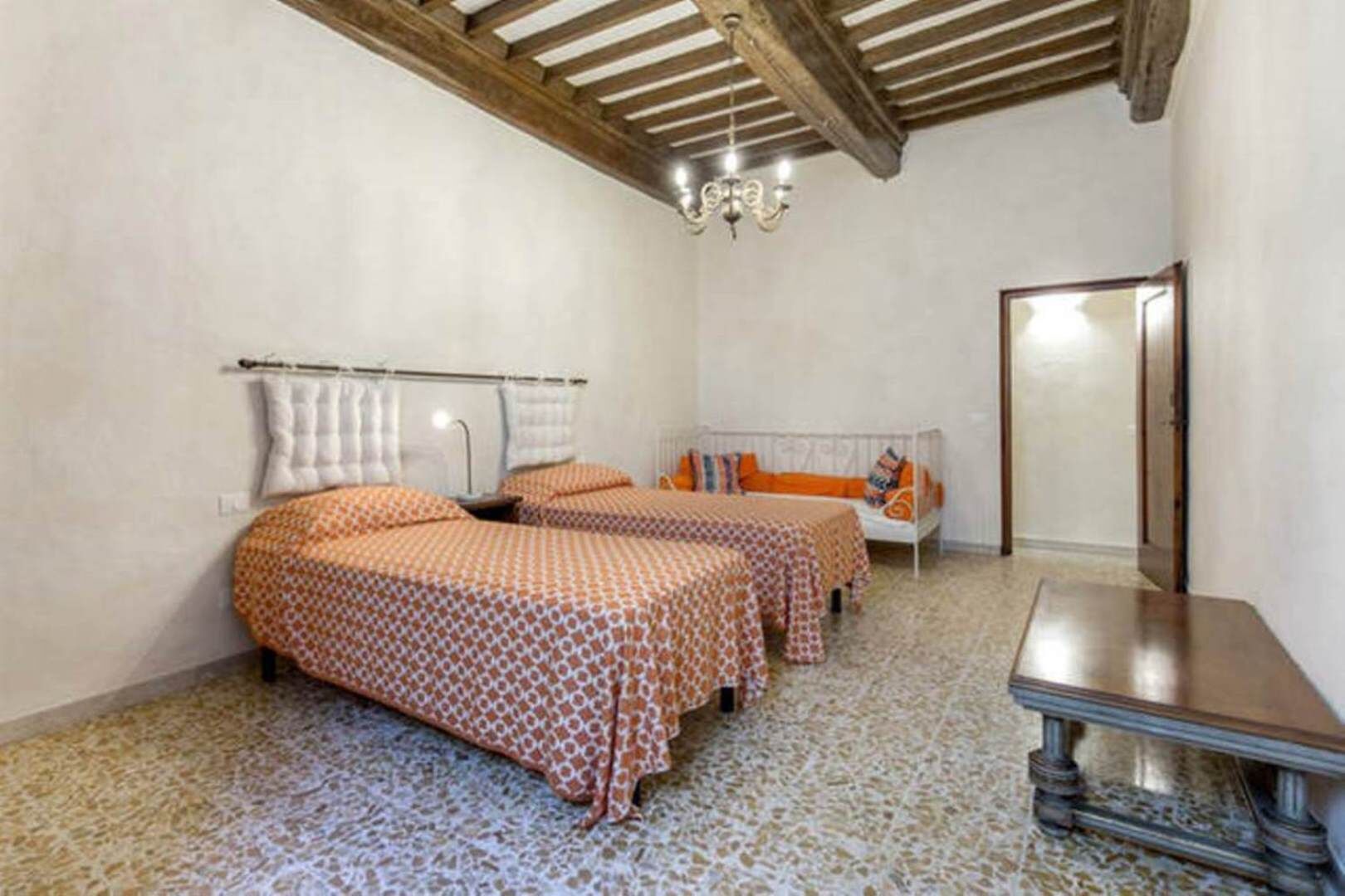 A room with two beds, a small table, and a mirror.