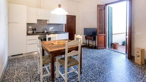 A compact kitchen with white cabinets, a wooden dining table, and a blue speckled floor. - "TERRACE BELL" (PANZANO IN CHIANTI)