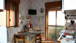 A kitchen with a dining table, chairs, a television, and a window with a view.