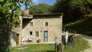 A stone building with a door, windows, and a small garden area with a fence. - Mimmo Holiday House Florence (San Godenzo, Firenze)
