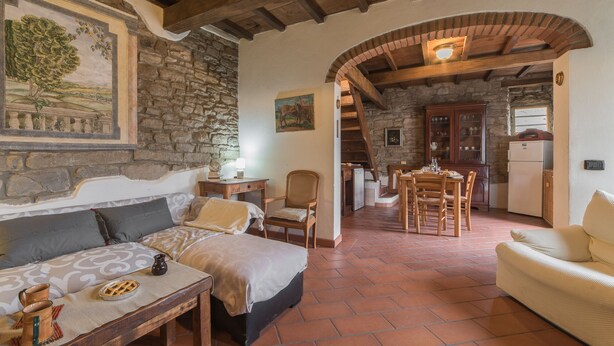 A cozy room with a bed, a wooden table, and a dining area with chairs. - Mimmo Holiday House Florence (San Godenzo, Firenze)