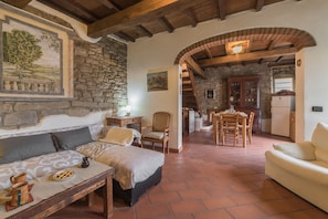 A cozy room with a bed, a wooden table, and a dining area with chairs.