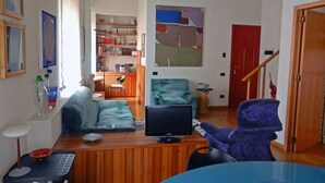 Un espacio habitable compacto con televisor, sofá, sillón y una mesita.