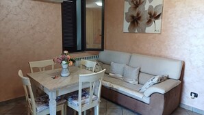 Un coin repas avec une table et des chaises, un canapé et un climatiseur fixé au mur.