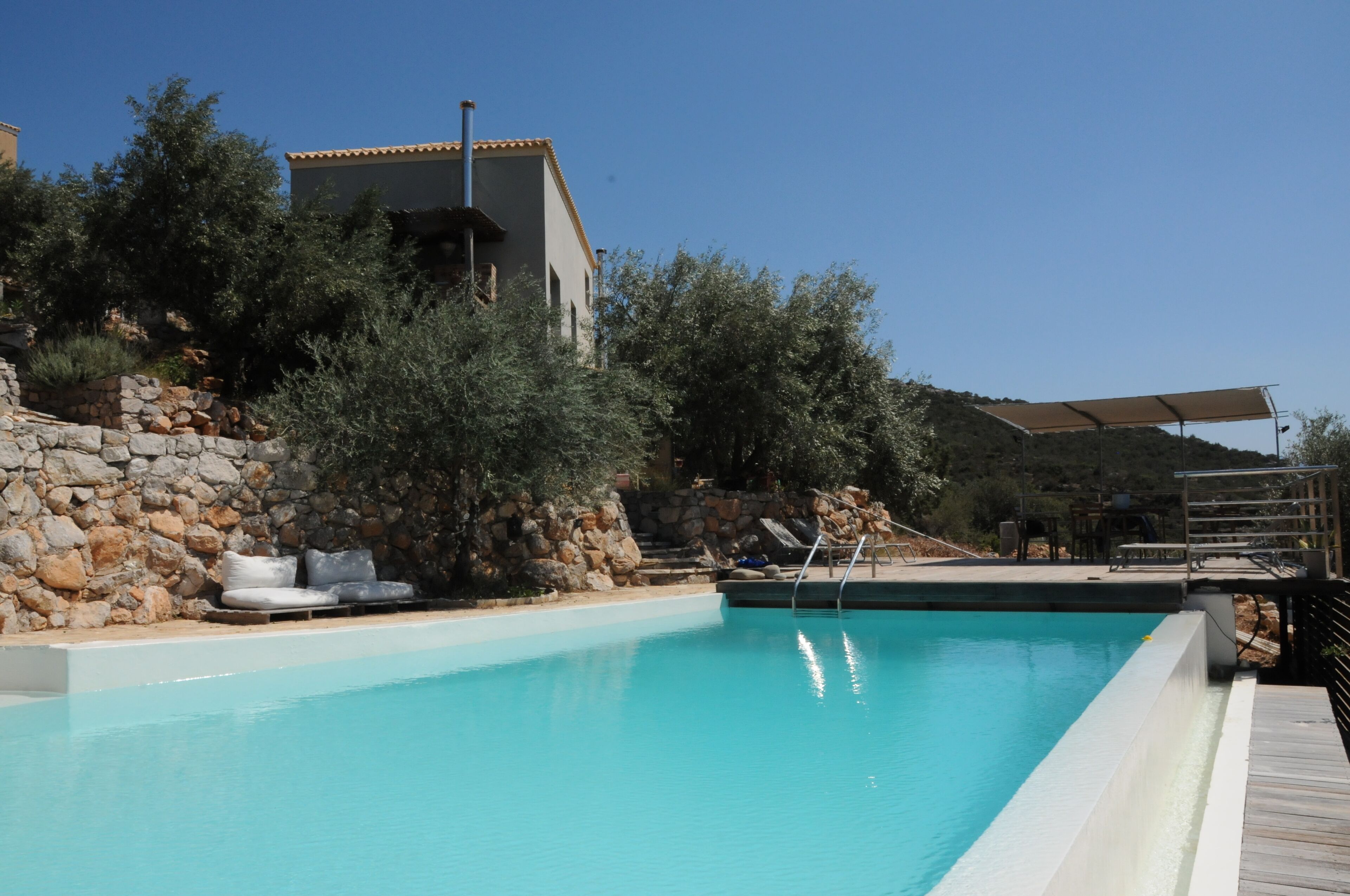 Une piscine avec un mur en pierre et un bâtiment en arrière-plan.