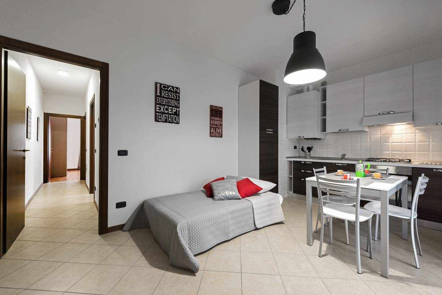 A compact living space with a kitchenette, a dining area, and a small bed.