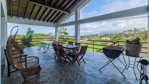 Una veranda coperta con pavimento in pietra, arredi da esterno e vista sul paesaggio.