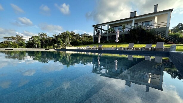 Una casa moderna con piscina, immersa nel verde sotto un cielo limpido.