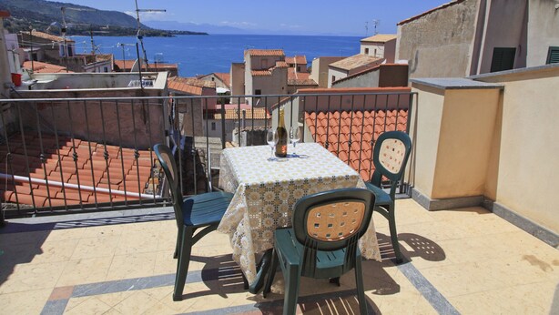 Un balcon avec une table et des chaises donnant sur une vue panoramique de la côte.