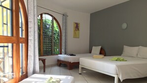Een kamer met twee bedden, een tafeltje en een raam met gordijnen.