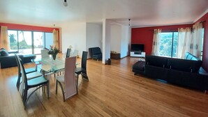 A spacious living area with a dining table, chairs, a sofa, and a TV. - Villa Luz: between Serra and the Sea - Free Wifi (Santa Cruz)