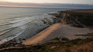 A coastal landscape with a beach, cliffs, and a sea view.