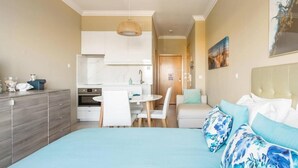 A modern bedroom with a large bed, a dining area, and a kitchen.