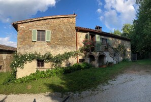 A rustic stone house with a small balcony and a staircase leading to a second level. - Bargi House (Perugia)