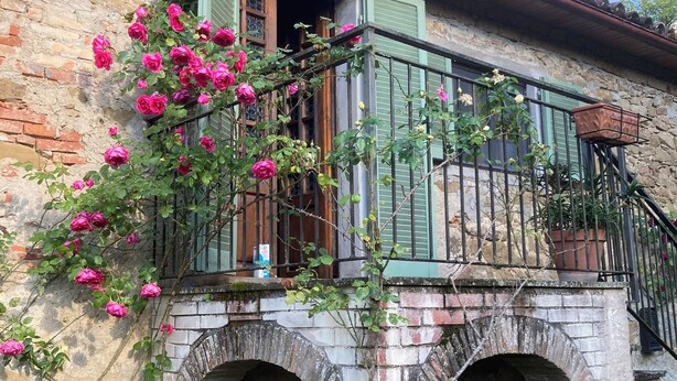 A rustic building with a stone facade, a balcony with green shutters, and a brick archway. - Bargi House (Perugia)