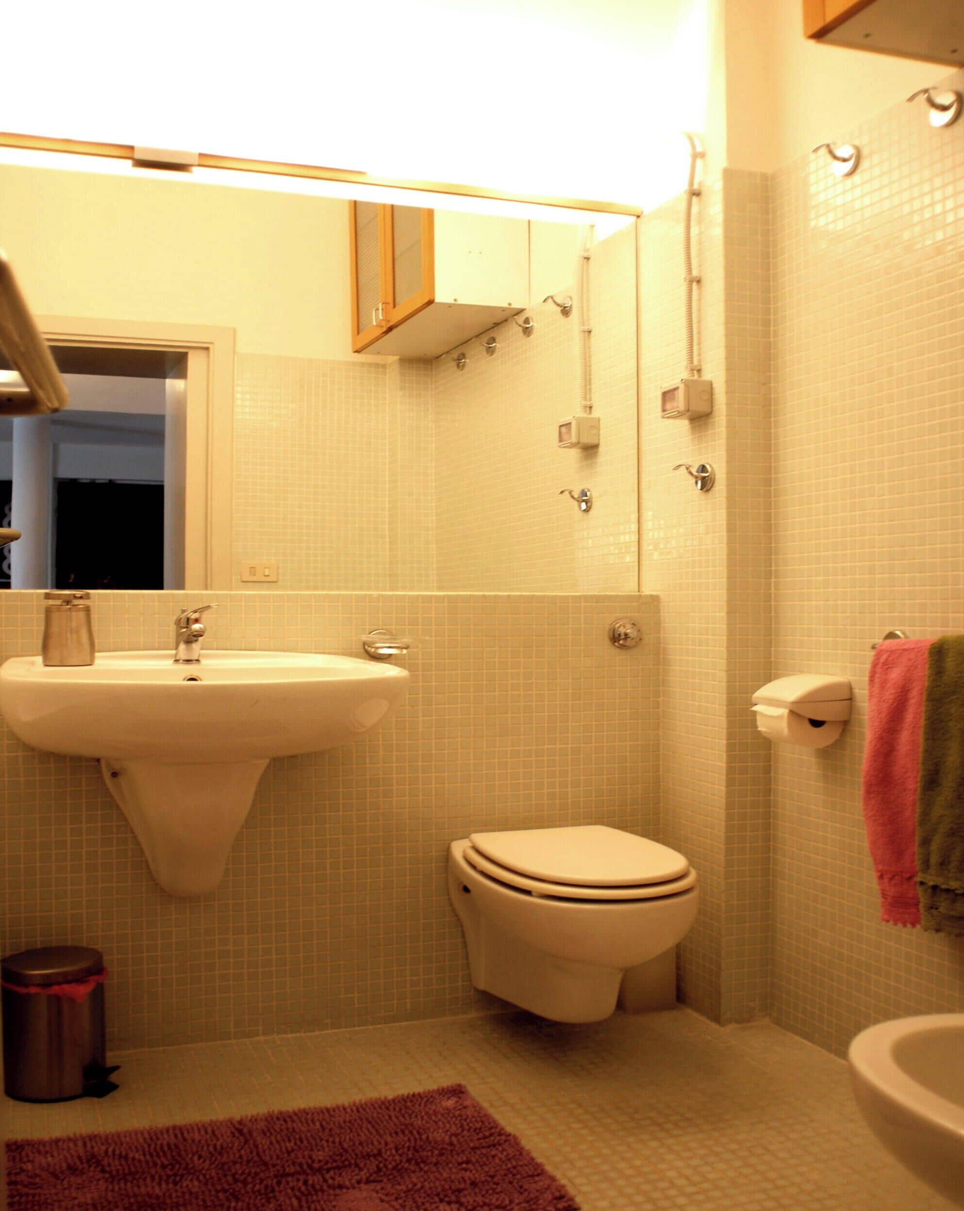 A compact bathroom with a sink, toilet, and a mirror above the sink.