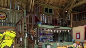Een rustiek interieur met houten balken, een groene toonbank en een trap naar een hoger gelegen verdieping.