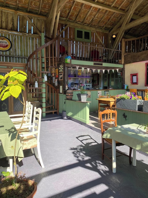 Un interior rústico con vigas de madera, una barra verde y una escalera que lleva a un nivel superior.