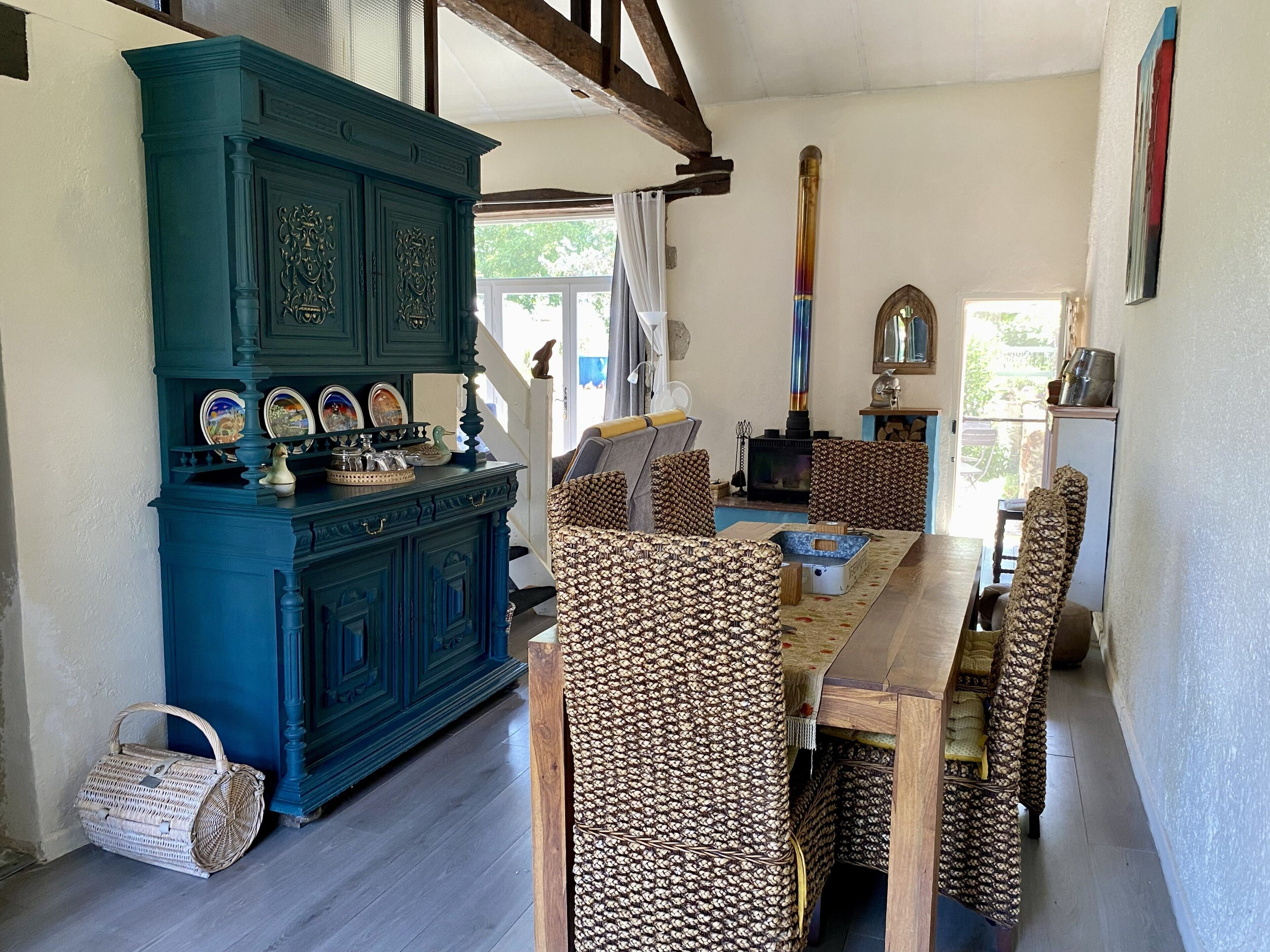 Un coin repas avec une table et des chaises en bois, un buffet bleu et une cheminée.