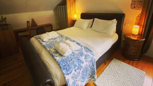 Ein Schlafzimmer mit einem Bett, Nachttischlampen, einer Holzbk und einem gemusterten Teppich.