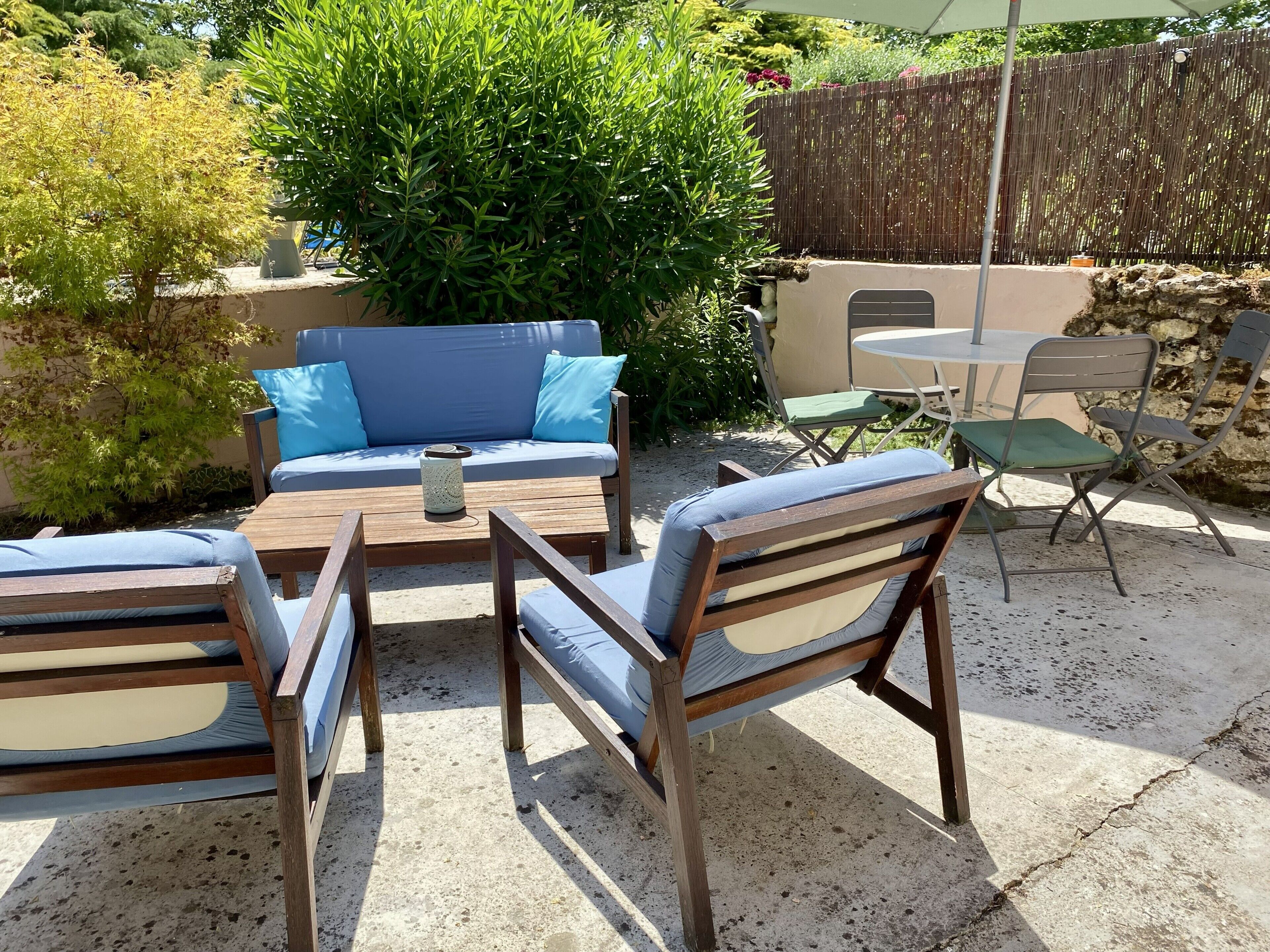 An outdoor patio with a sofa, chairs, a table, and a small garden area.