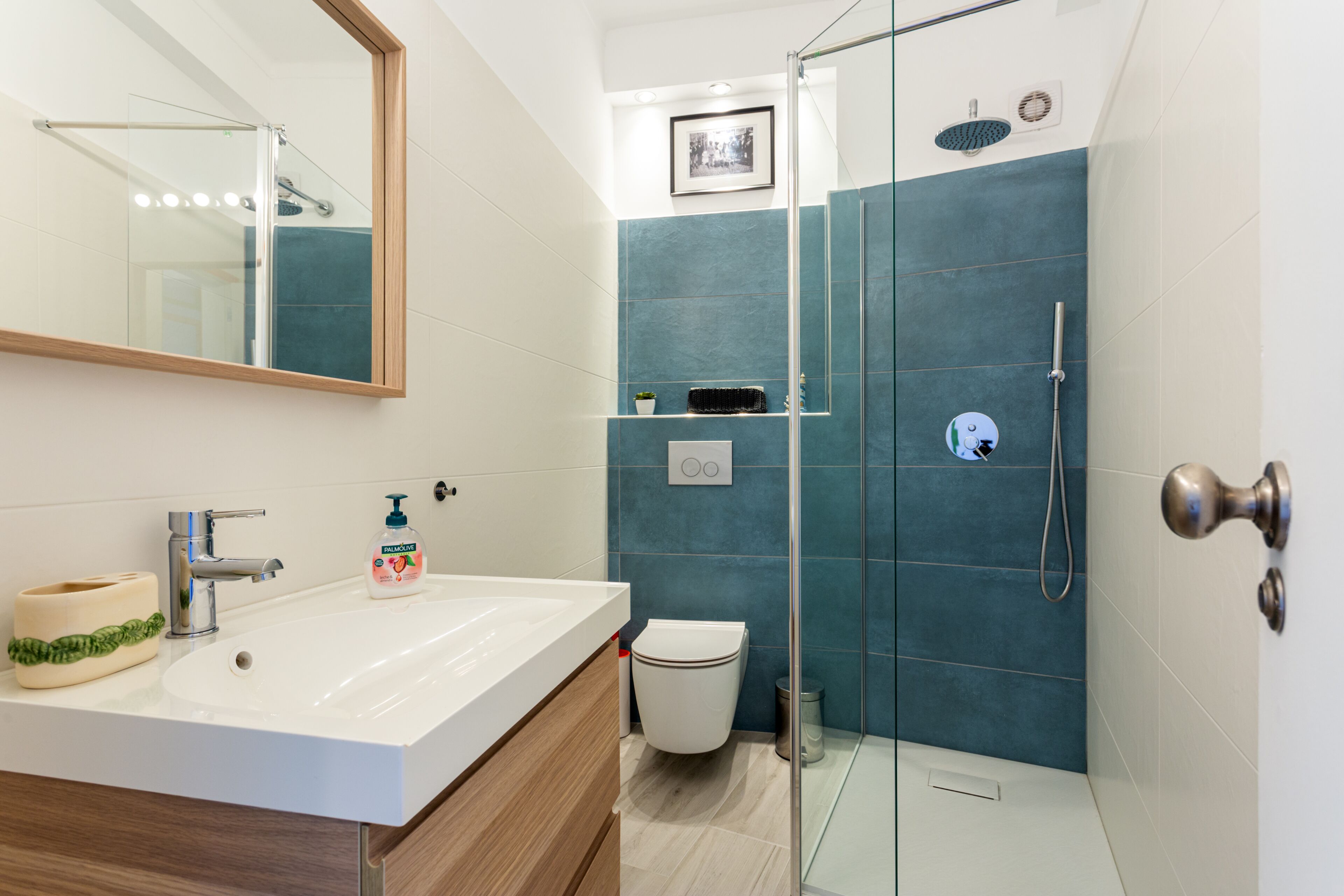 A modern bathroom with a glass shower enclosure, a white sink, and a mirror.