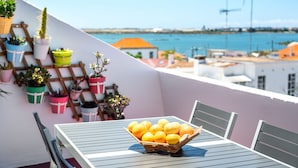En balkon med et bord, stole, en kurv med citroner og plantekasser.