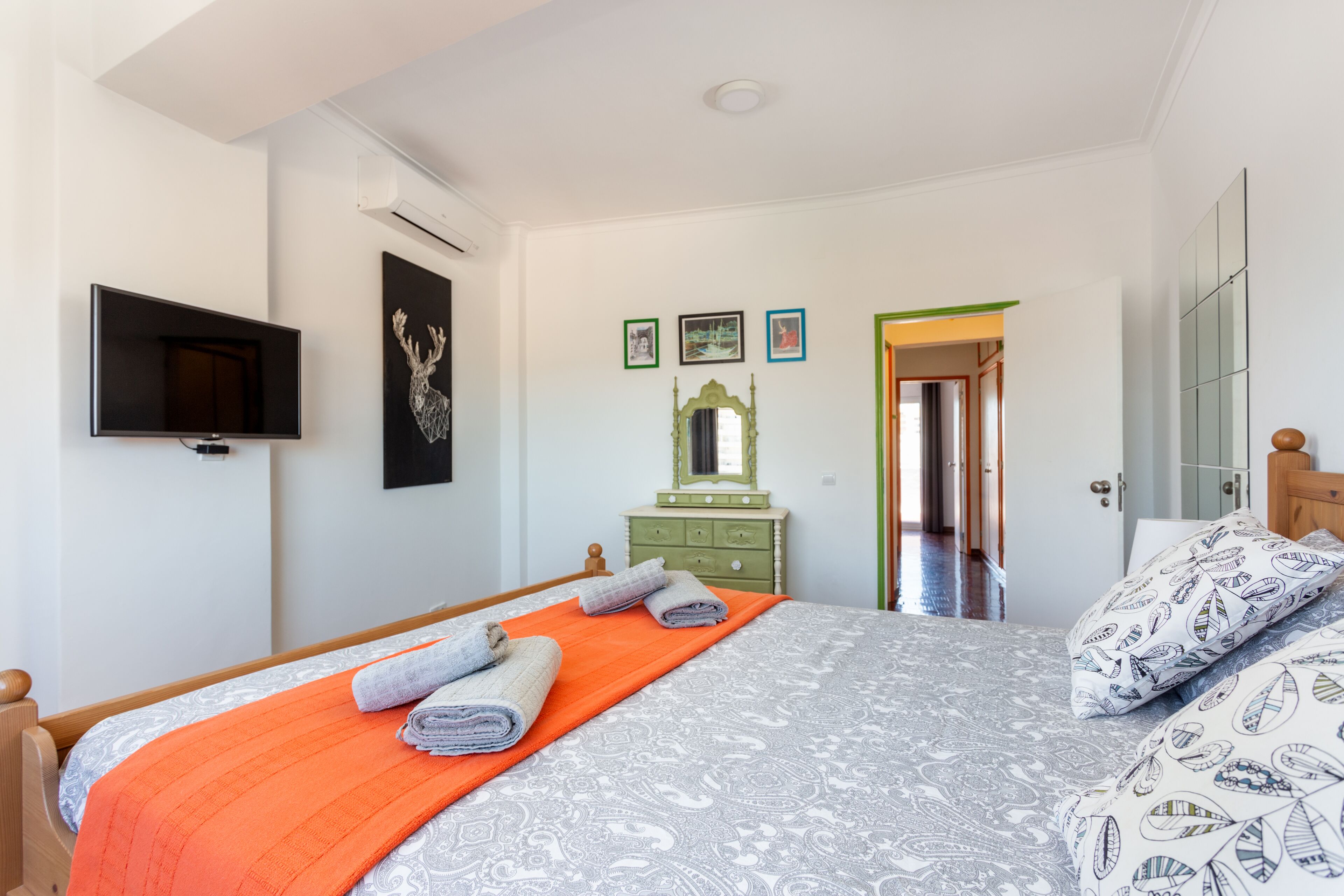 Un dormitorio con cama, televisión, cómoda y espejo.