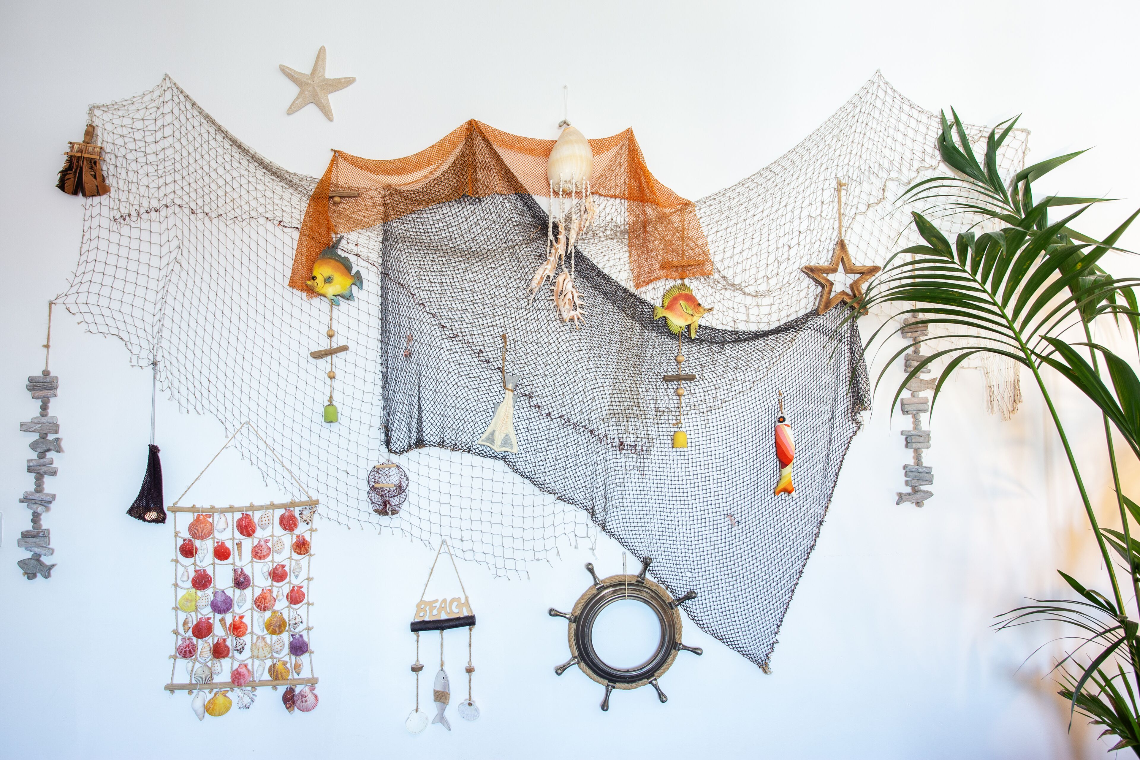 A wall decorated with various hanging items including a net, starfish, and a ship's wheel.