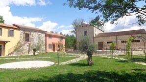 Un patio con edificios de piedra, un área pavimentada y un árbol pequeño.