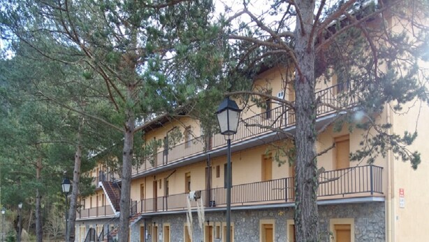 A two-story building with stone walls and balconies. There are multiple doors and windows, and a staircase leading to the upper floor. - Gite in the Pyrenees (Guardiola de Berga)